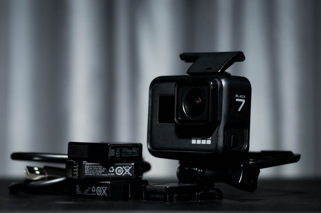 Detailed view of a black action camera and batteries on a dark background.